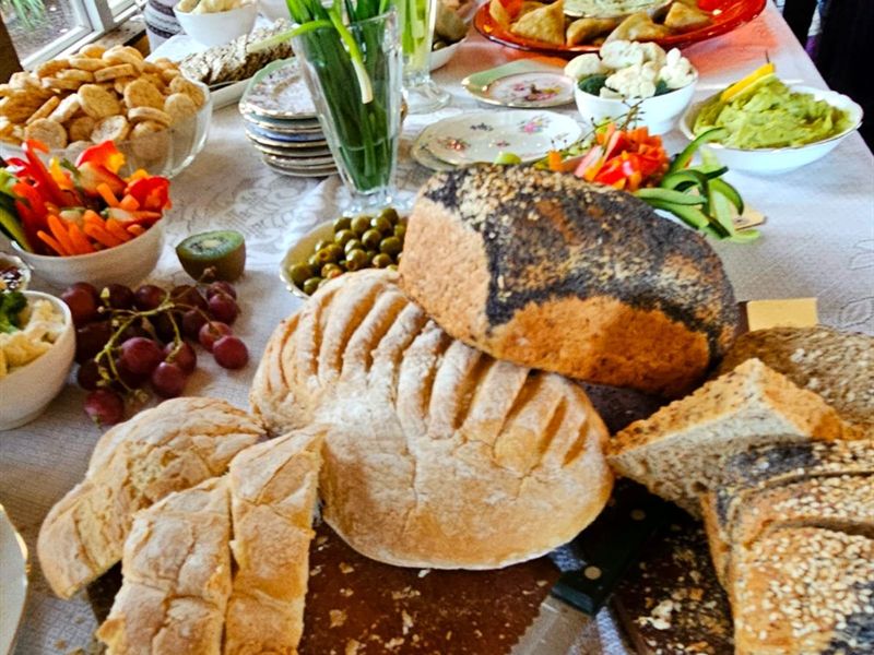 A market spread of home-baked breads, crackers, dips and fresh vegetables laid out on a long table.